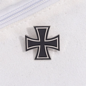 Classic black and silver alloy iron cross metal brooch pinned on white canvas background