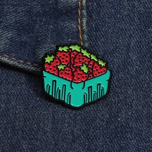 Détail d'une broche en émail panier de fraises épinglée sur du denim aux couleurs vives
