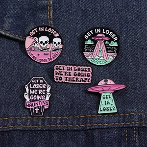 Set of 5 enamel pins with UFO, skull, and ghost designs on dark blue denim fabric