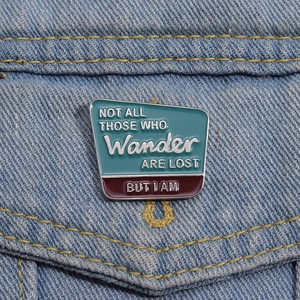 Badge émaillé rouge et bleu avec slogan de voyage sur veste en jean bleue