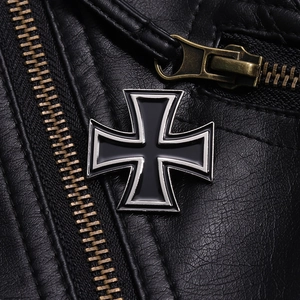 Macro detail of a black enamel Iron Cross metal badge on a textured leather jacket