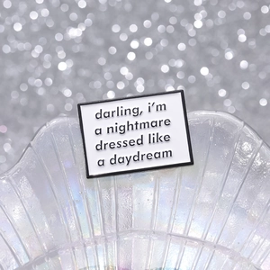 Detail of enamel quote brooch saying darling i'm a nightmare dressed like a daydream