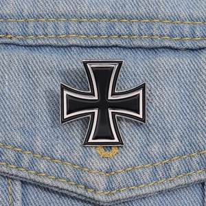 Close-up of a black enamel Iron Cross metal badge pinned on blue denim fabric