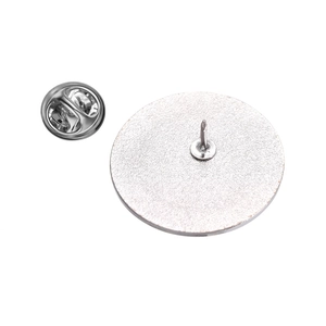 Detail view of the silver metal badge back featuring a sharp pin and butterfly clasp
