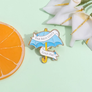 Kreative Emaille-Brosche in Regenschirmform mit Motivationsspruch auf frischem Hintergrund
