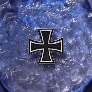 Detail of metal Iron Cross badge with black enamel finish and silver border on blue background