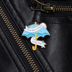 Blaue Regenschirm Emaille Brosche mit Schriftzug auf schwarzer Lederjacke dekoriert