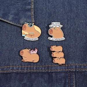 Detail view of four cute enamel capybara badges on blue denim fabric background