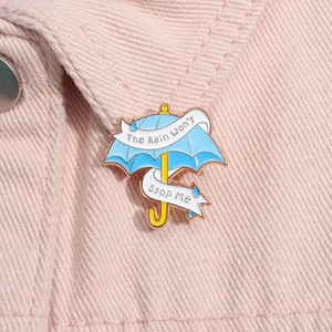 Detail der Emaille-Anstecknadel Regenschirm mit Text auf einer rosa Jacke