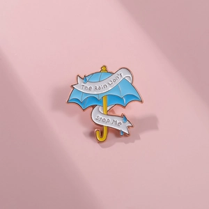 Detail der blauen Emaille-Regenschirm-Brosche mit dem Spruch The Rain Won't STOP Me und Roségold