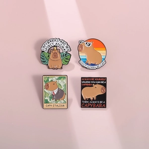 Detail view of four unique enamel capybara badges featuring cute animal illustrations