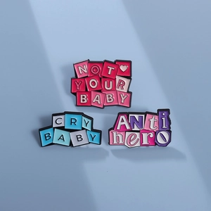 Drei bunte Emaille-Pins mit den Texten Cry Baby und Anti Hero auf blauem Grund