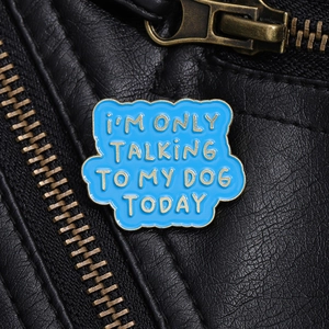 Gros plan d'un pin's en émail bleu sur veste en cuir avec message I'm only talking to my dog