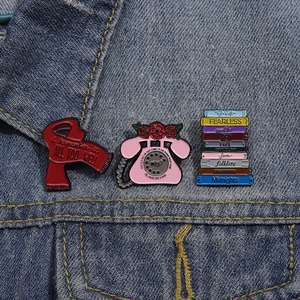 Detailansicht von drei Taylor Swift Emaille-Pins auf einer blauen Jeansjackentasche