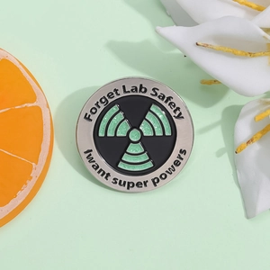 Detail of glitter enamel pin featuring Forget Lab Safety and super powers text quote