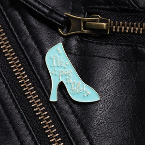 Detail of light blue high heel enamel brooch with It's possible text on a leather jacket