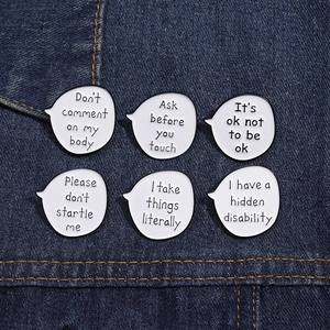 Detail of 6 white speech bubble enamel pins with text on dark blue denim fabric