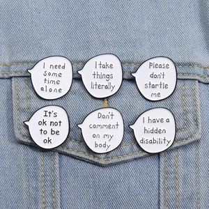 Detail of six white enamel speech bubble brooches on a blue denim jacket pocket