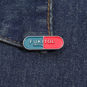 Macro detail of red and blue enamel Fukitol capsule brooch pin on denim fabric