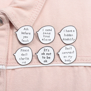 Detailed close-up of six white enamel conversation bubble pins on pink denim fabric