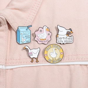 Détail de cinq pin's émaillés Silly Goose sur denim rose avec illustrations de canards