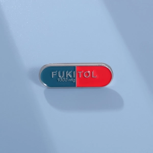 Funny FUKITOL capsule enamel pin with red and blue contrast design on light blue background