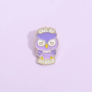 Detail shot of purple owl enamel brooch with golden metal outlines and teardrop design