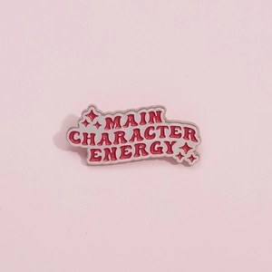 Detailweergave van de rode emaille speld met de tekst Main Character Energy