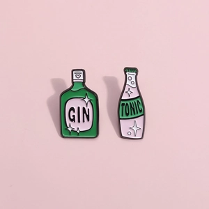 Cartoon gin and tonic bottle enamel brooch set with starry details on a pink background