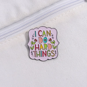 Detail of I CAN DO HARD THINGS enamel pin with flower pattern on white canvas bag