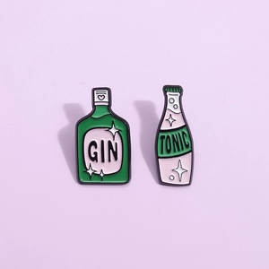 Detail of Gin and Tonic enamel pins set with green and pink lacquer on purple background