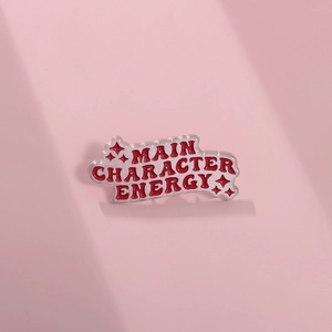 Detail van de Main Character Energy emaille speld met rode letters en zilveren plating