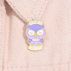 Cartoon purple owl enamel pin with Owl By Myself text on pink fabric background