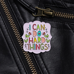 Inspirational enamel pin with I CAN DO HARD THINGS text on black leather jacket