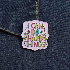 Detail view of light purple enamel pin with floral motifs on blue denim fabric