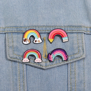 Vier bunte Regenbogen-Emaille-Pins an einer hellblauen Jeansjacke in detaillierter Ansicht