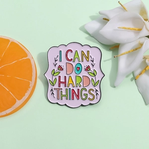 Detail of lavender enamel pin with flowers and I CAN DO HARD THINGS slogan