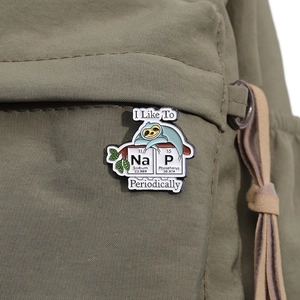 Detailed close-up of sloth enamel pin with funny chemical element pun on a green canvas bag