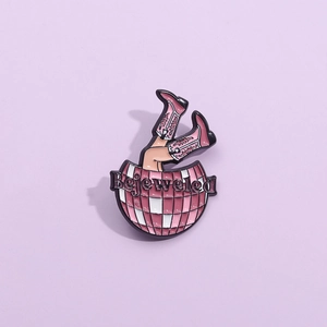 Détail d'un pin's en émail avec texte Bejeweled, boule disco et bottes de cowboy rose