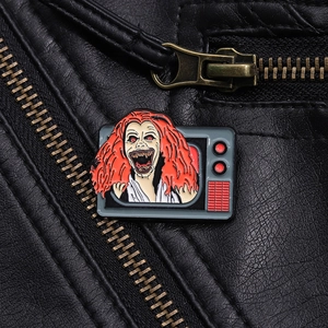 Macro shot of horror character enamel pin crawling out of TV on leather jacket