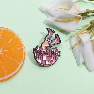 Broche en émail boule disco Bejeweled de Taylor rose avec bottes de cowboy sur fond vert