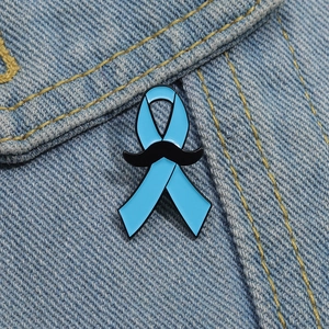 Vue macro d'un pin's ruban bleu avec moustache noire sur un tissu en denim bleu clair
