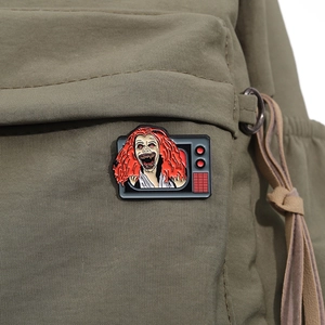 Detail of horror TV enamel pin with red hair monster on green canvas backpack