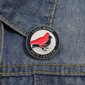Close-up of bird enamel pin on denim jacket featuring Love Birbs Hate Fascism text