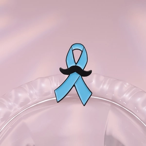 Détail de la broche en émail ruban bleu clair avec moustache noire sur fond en tissu