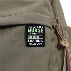 Rectangle enamel pin with nursing theme on green canvas bag showing high quality details