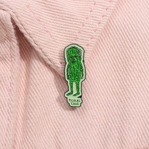 Detailed view of the green Picolas Cage enamel pin on a pink twill fabric collar