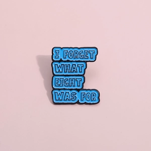 Detail of blue enamel pin featuring I FORGET WHAT EIGHT WAS FOR text and black outlines