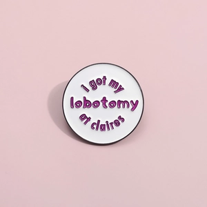 Macro shot of circular enamel pin featuring purple text on white background and black trim