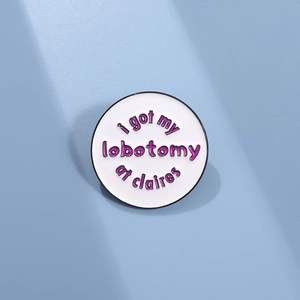 Close-up of white enamel pin badge with creative purple text on light blue background